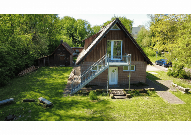 Drohnenansicht Haus mit Sicht auf Feuertreppe, Lagerfeuerplatz und Materialschuppen